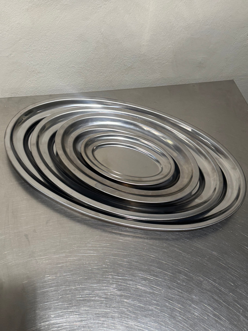 Four oval stainless steel serving trays