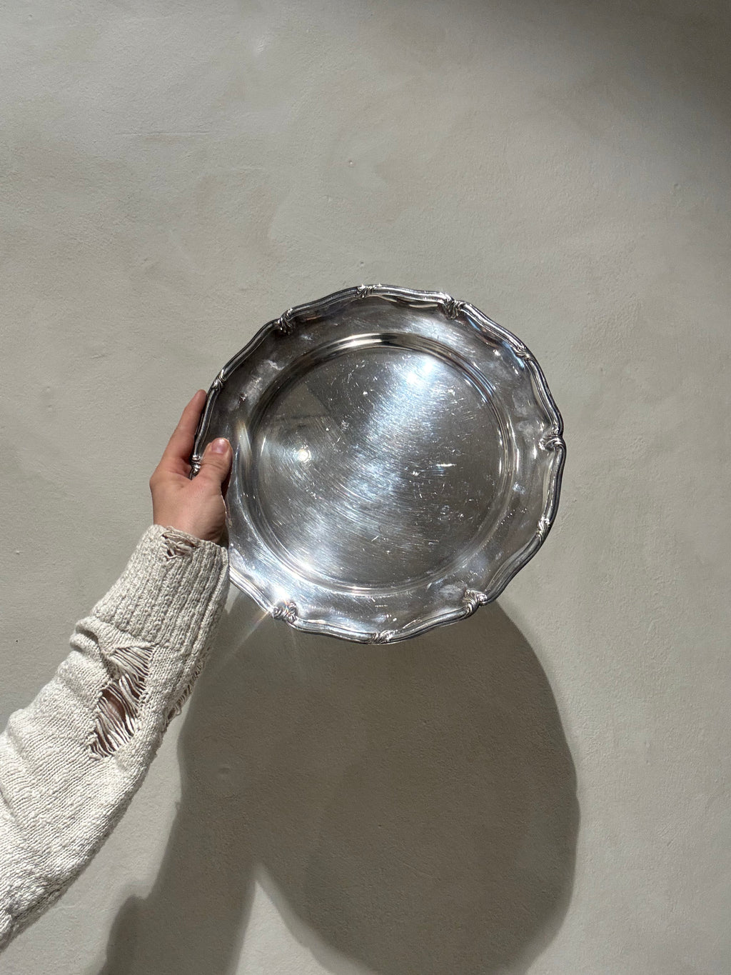 Round silver-plated tray held upright